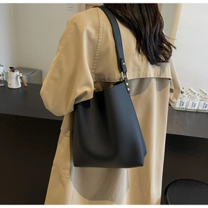 Close-up of black lychee grain tote bag worn with a light brown trench coat for daily commute