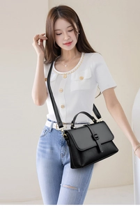 Close-up of black crossbody bag showing pebbled leather texture and glossy hardware