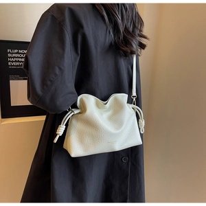 Détail macro du sac bandoulière beige en cuir texturé avec cordon de serrage et nœud