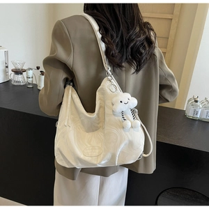 Close-up of cream marble textured tote bag with cute cloud charm in a cafe setting