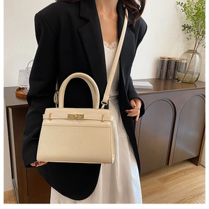 Detail of cream white leather handbag with gold clasp and slender strap in natural light