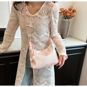 Detailed view of pink jacquard handbag with silk texture and floral tassel on white outfit