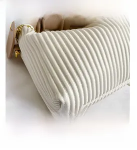 Close-up of white pleated leather texture with golden metal chain detail and leather tag