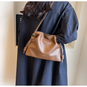 Détail du sac seau en cuir litchi caramel avec logo doré et finitions à cordon coulissant