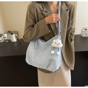 Detail of light blue marble pattern tote bag with a white plush cloud charm accessory