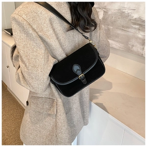 Detail of a matte black leather shoulder bag with a vintage gold metal buckle