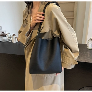 Detail of black lychee grain leather bucket bag showing its matte texture and soft drape