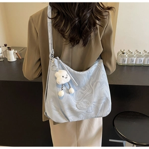 Close-up of a blue marble print tote bag featuring a cute cloud plush charm and logo label