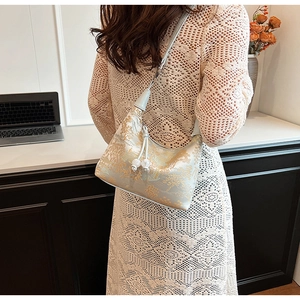 Detail of mint green jacquard bag with golden landscape patterns and silk tassel accents
