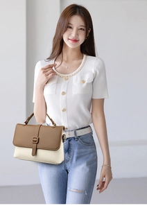 Close-up of contrast crossbody bag with brown flap and cream leather being carried by model
