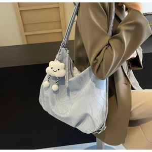 Detail of light blue textured tote bag with a white plush cloud charm for daily use