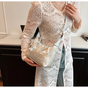Detail of light blue embroidered hobo bag featuring golden Chinese landscape patterns