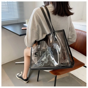 Detail of transparent PVC tote bag with black SUPPORT logo and leather shoulder handles