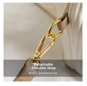 Detail of gold metal buckle and leather strap on white textured shoulder bag