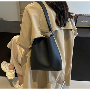 Detail of black pebbled leather texture and gold buckle on a minimalist tote bag