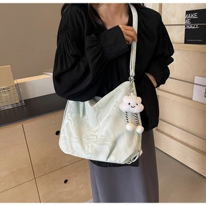 Detail of hobo bag with green marble pattern and white cloud plush pendant on shoulder strap