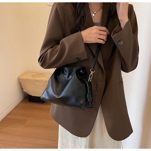 Détail du sac seau noir en cuir grainé avec cordon de serrage et finitions dorées