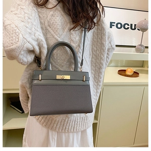 Detail of grey trapezoid handbag with twill fabric texture and golden swivel lock