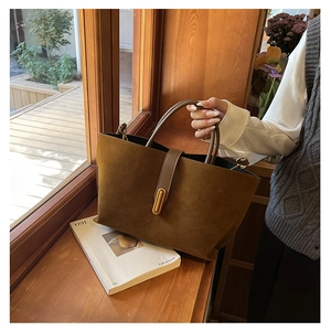 Detail of vintage brown tote bag with suede texture and elegant gold buckle on a windowsill