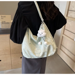 Close-up of light green marble texture tote bag with a cute cloud plush charm