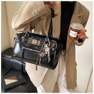 Detail of black glossy leather bag featuring silver hardware and decorative bag charms