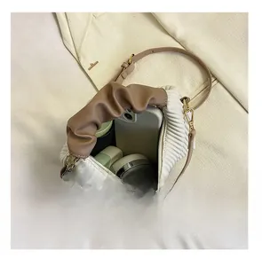 Internal storage detail showing a smartphone and cosmetics in a beige pleated handbag