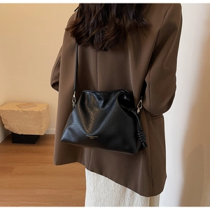 Détail du sac seau noir avec cordon de serrage montrant la texture en cuir et le logo