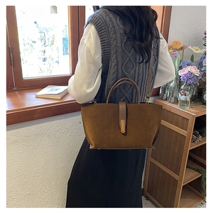 Detail of vintage brown suede handbag with golden metal clasp and tubular handle