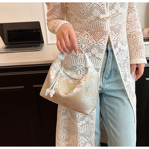 Close-up of light blue satin embroidery handbag with traditional golden cloud patterns