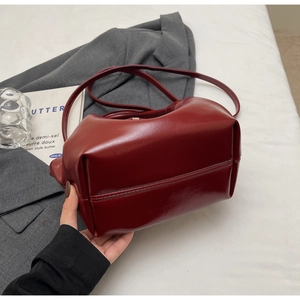 Détail du sac cabas bordeaux brillant en similicuir avec coutures sur fond blanc