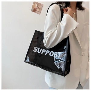 Detail of black transparent PVC tote bag with white SUPPORT lettering on model