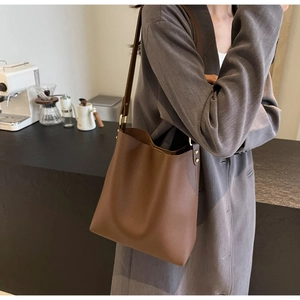 Detail of dark brown lychee leather bucket bag with golden hardware and adjustable strap