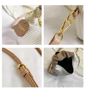 Detailed views of gold hardware, khaki leather tags, and white pleated fabric on a bag