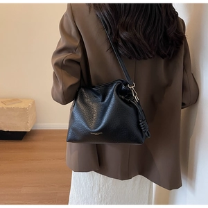Sac seau en cuir grainé noir avec cordon de serrage porté par un mannequin chic
