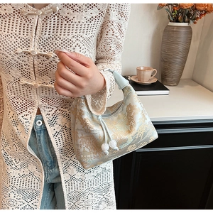 Detail of light blue Chinese style handbag with golden mountain embroidery and pearl charms
