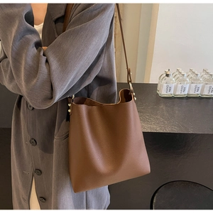 Detail of brown litchi pattern leather tote bag with metal rivets and strap
