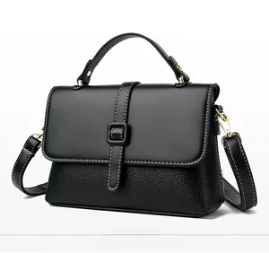 Detail of black dual-texture handbag featuring lychee pattern and gold hardware accents
