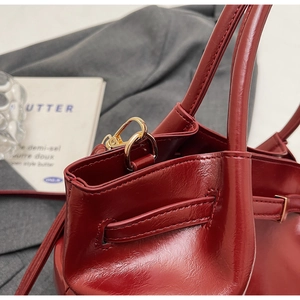 Gros plan du sac cabas en cuir verni rouge foncé avec crochets en métal doré poli
