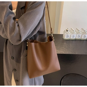 Close-up of brown litchi pattern leather bucket bag with fine shoulder straps and gold hardware