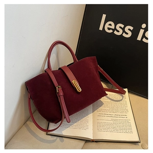 Detail view of burgundy leather and suede tote bag with elegant gold metal clasp