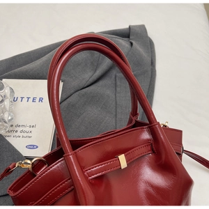 Détails d'un sac cabas bordeaux brillant avec des ferrures dorées et des anses