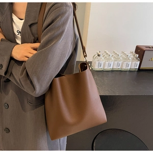 Detail of brown lychee texture leather bucket bag with metal ring and shoulder strap