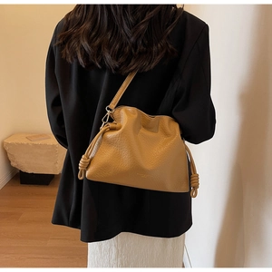Détail du sac seau en cuir jaune gingembre avec cordon plissé et texture litchi