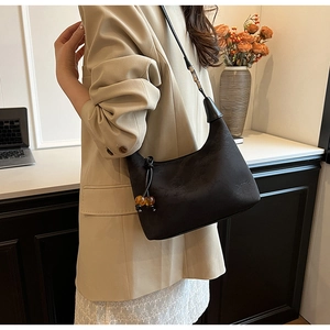 Close-up of black New Chinese style hobo bag with amber bead charm and matte texture