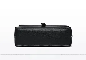 Detail of the rectangular bottom of the black lychee leather bag with white stitching