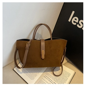 Close-up of brown frosted suede tote bag with golden metal clasp and leather handle