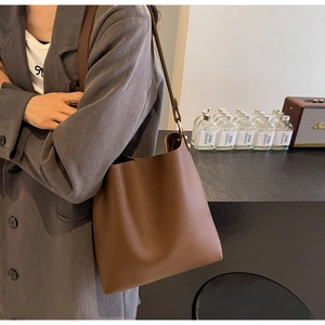 Detail of brown litchi-grain leather tote showing texture and thin shoulder strap design