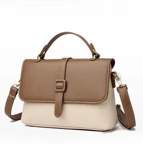 Close-up of beige and brown leather contrast stitching and gold buckle on handbag