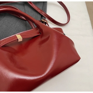 Détail du sac à main rouge brillant avec boucle en métal doré élégante et texture lisse