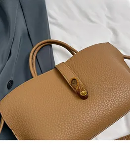 Detailed macro view of brown lychee grain leather tote with golden rectangular twist lock